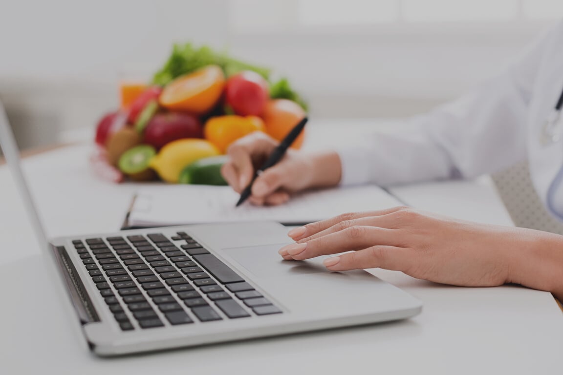 Nutritionist doctor writing diet plan on table